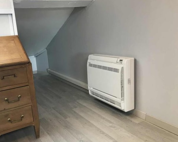Console de climatisation posée au ras du sol dans une chambre sous combles