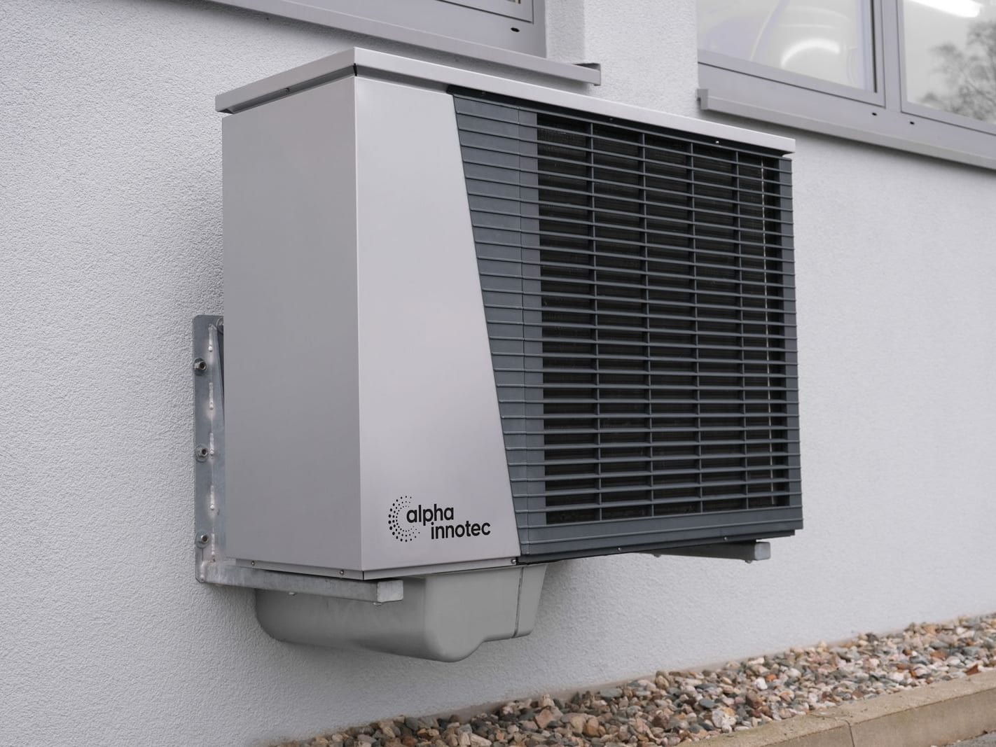 Unité extérieure de pompe à chaleur air-eau posée sur console le long d'une façade