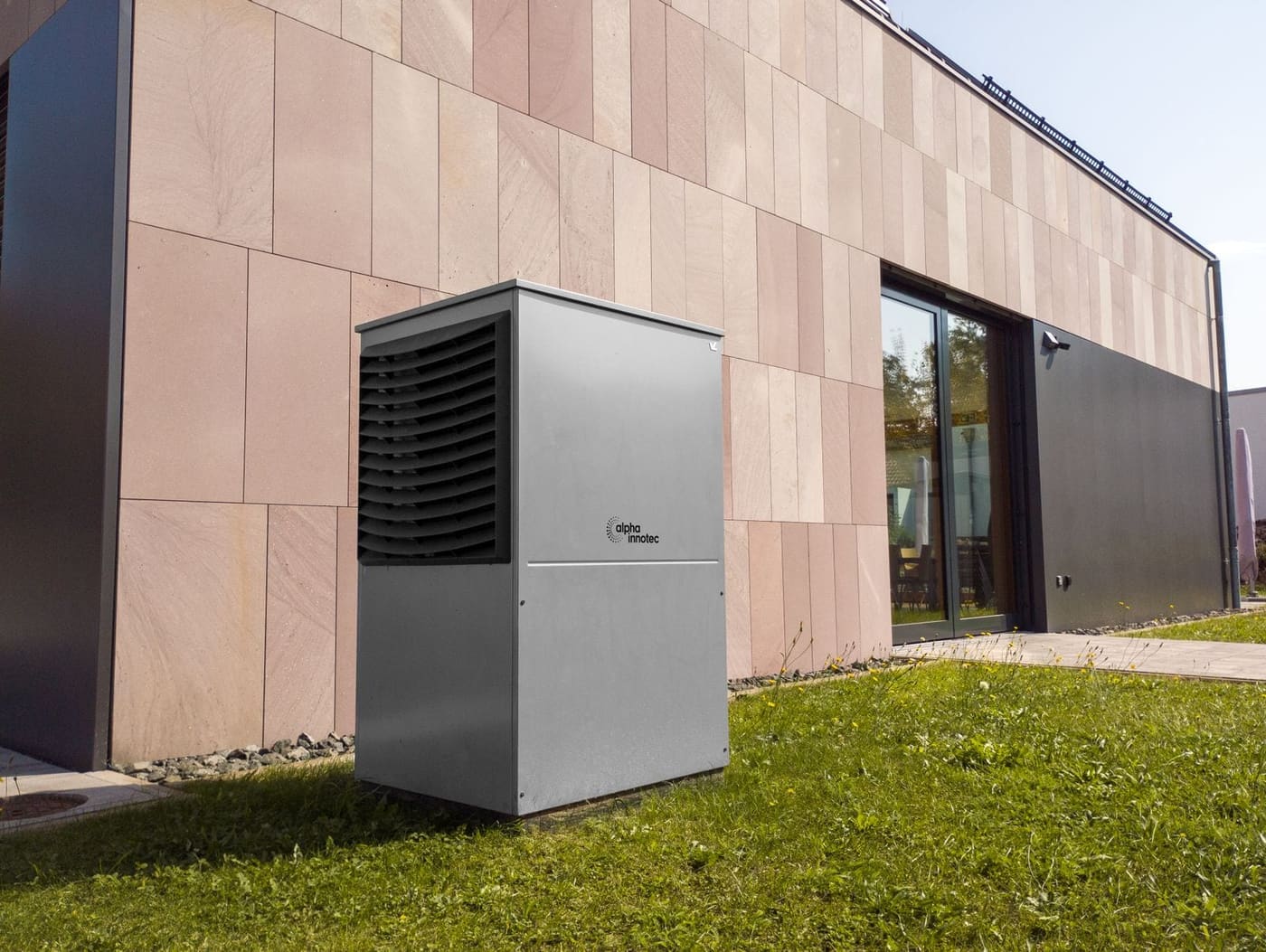 Pompe à chaleur air-eau posée sur pelouse devant une maison contemporaine