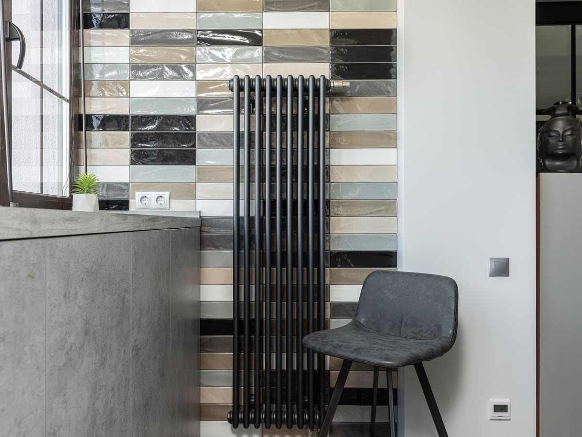 Radiateur acier vertical et thermostat dans une pièce chauffée